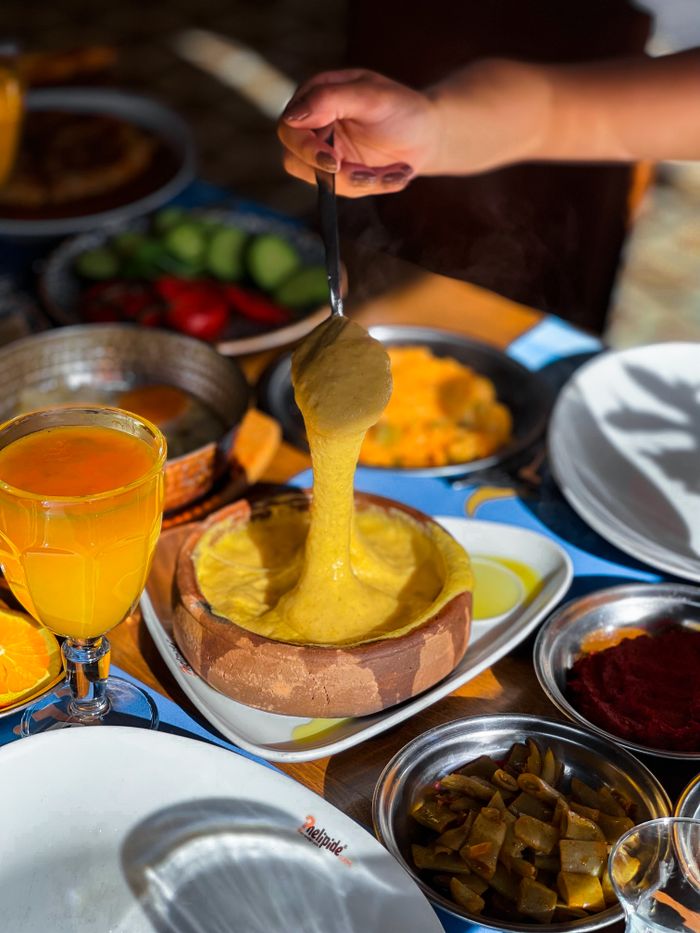 A vibrant Turkish breakfast featuring cheese fondue and various side dishes on a table.